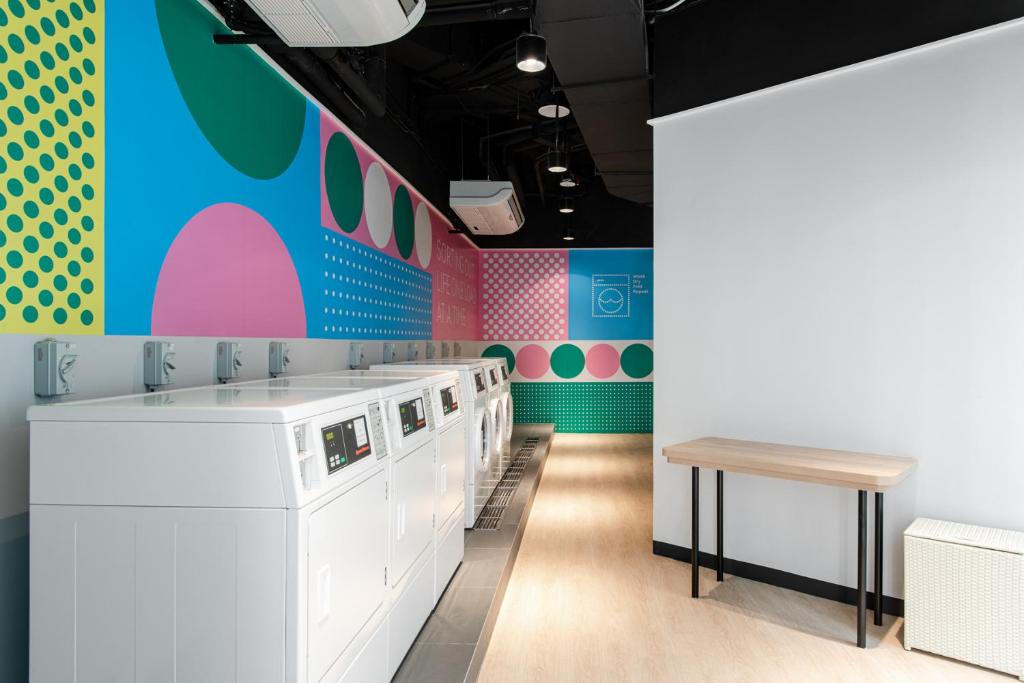 a laundry room with washing machines and a bench at Komune Living in Kuala Lumpur