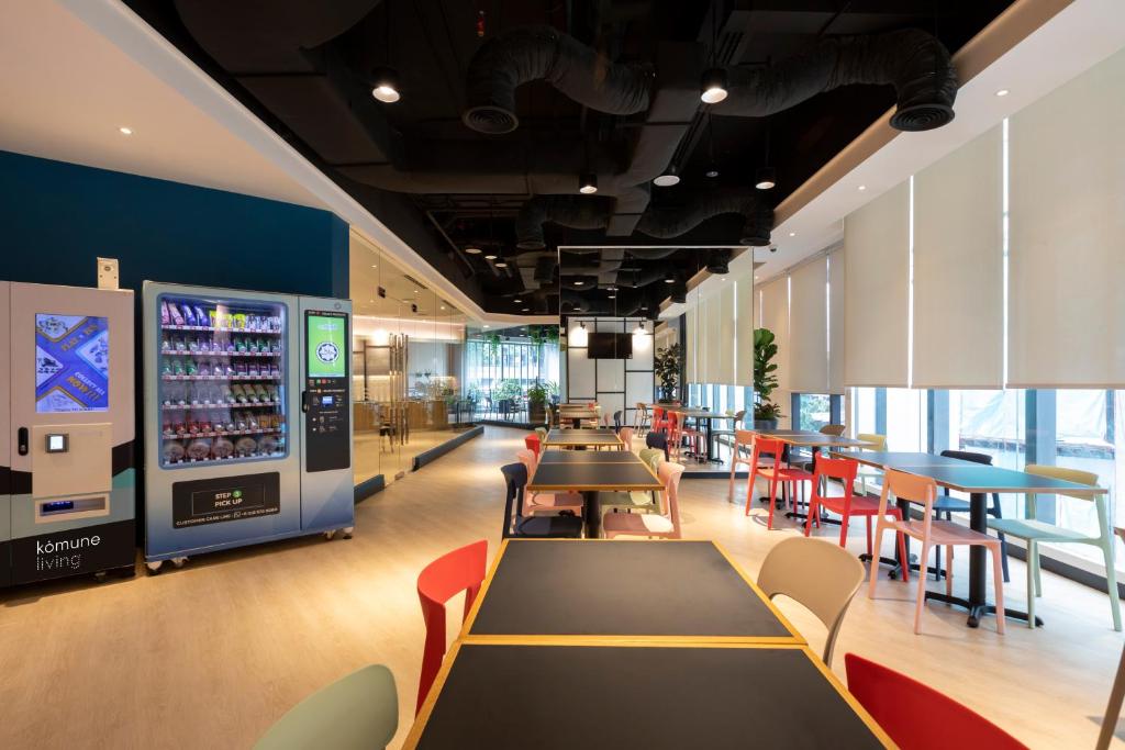 a restaurant with tables and chairs and a drink machine at Komune Living in Kuala Lumpur