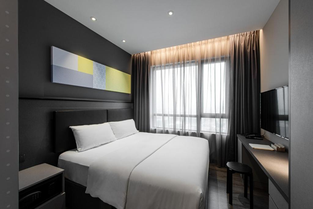 a bedroom with a bed and a desk and a window at Komune Living in Kuala Lumpur