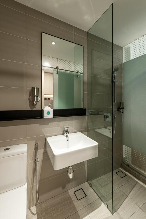 a bathroom with a sink and a glass shower at Komune Living in Kuala Lumpur