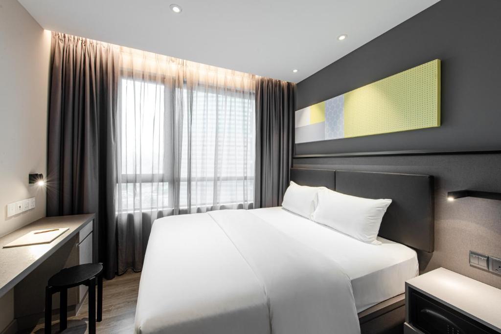 a hotel room with a white bed and a desk at Komune Living in Kuala Lumpur