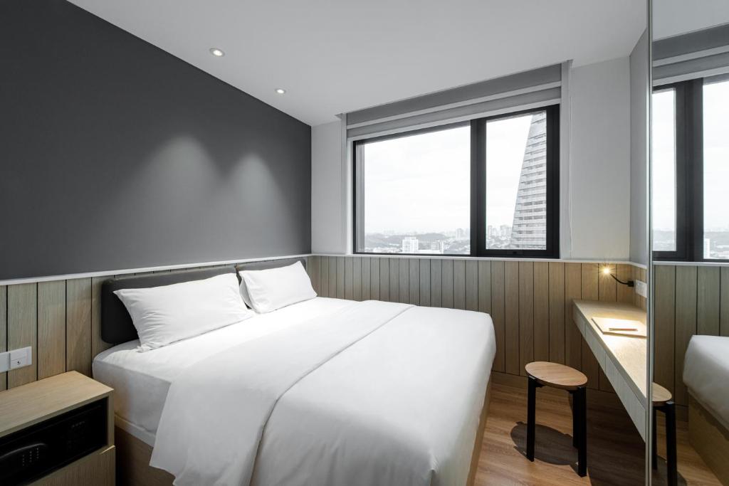 a bedroom with a large white bed and windows at Komune Living in Kuala Lumpur