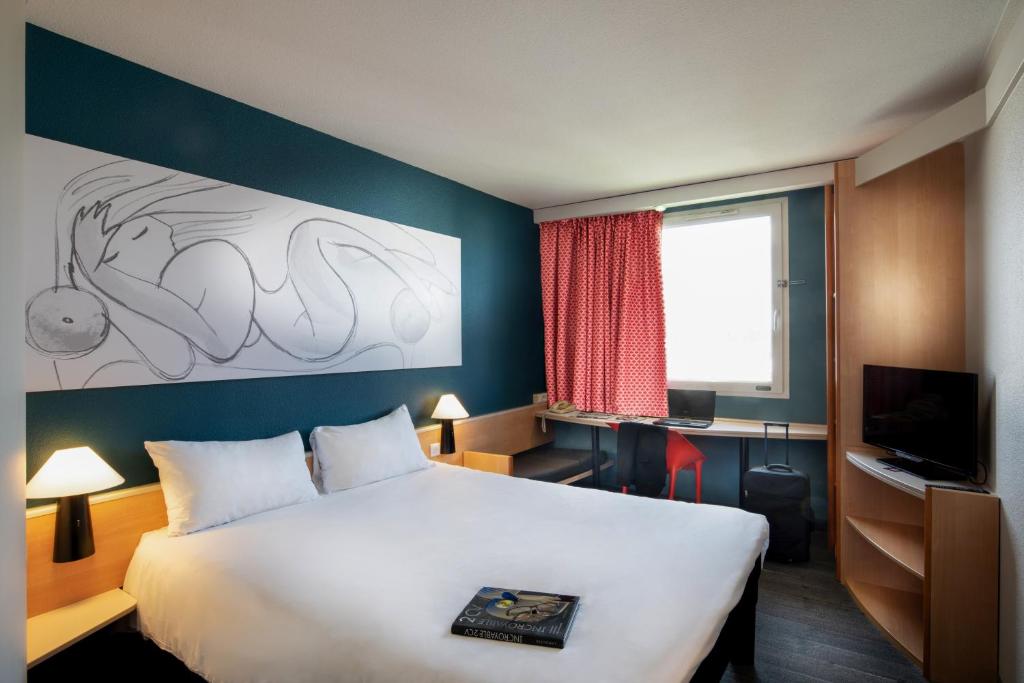 a hotel room with a large bed and a television at ibis Thionville Porte du Luxembourg in Basse-Yutz