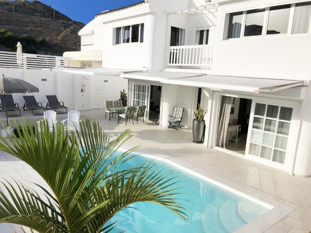 a white house with a swimming pool in front of it at Sea view villa San Agustin vista Claveles in San Agustin