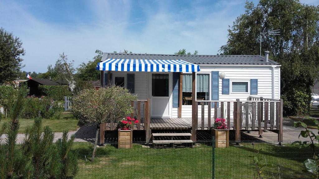 uma pequena casa branca com um toldo azul e branco em Camping les Charmilles em Houlle