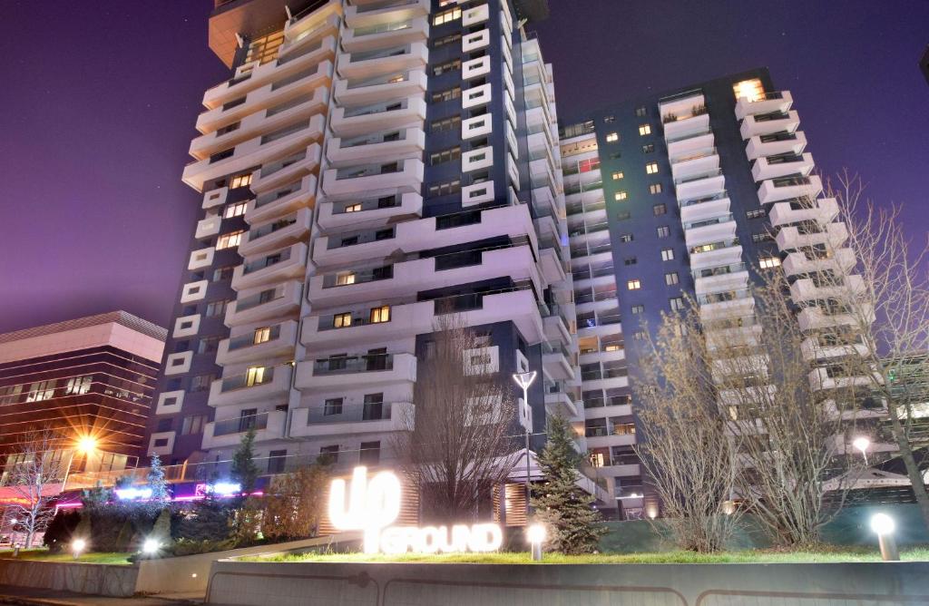 a tall white building at night with buildings at Upground Residence Apartments in Bucharest