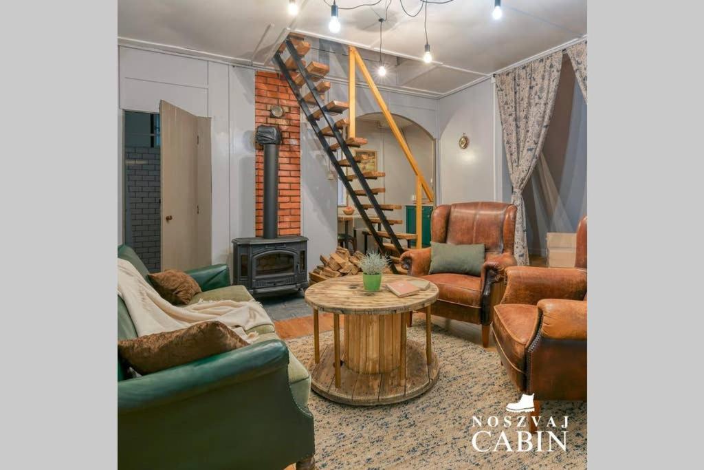 een woonkamer met banken, een tafel en een trap bij Noszvaj Cabin in Noszvaj