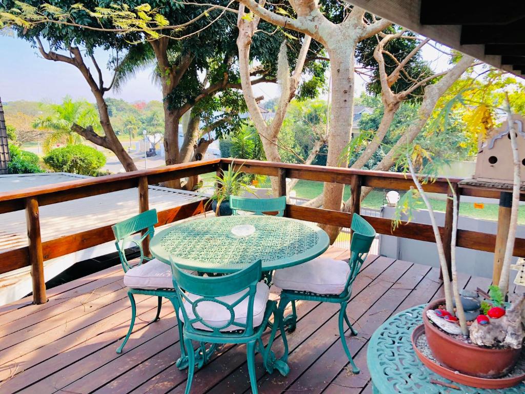 a table and chairs on a deck with trees at MaBella in Richards Bay