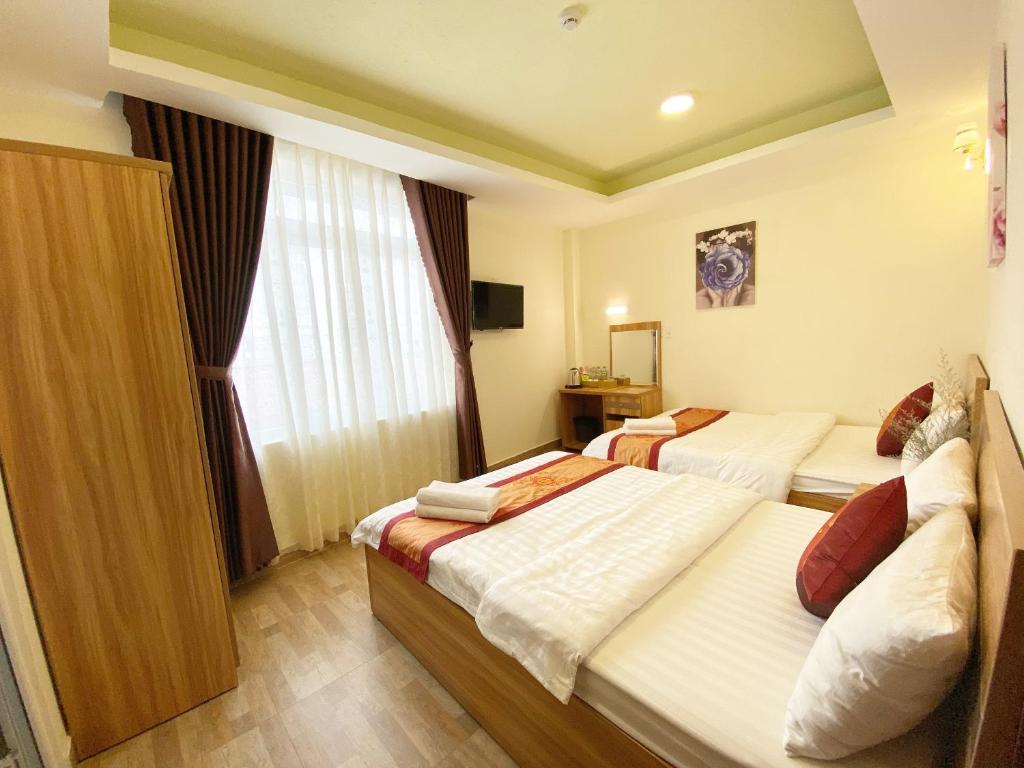 a hotel room with two beds and a window at Vanilla Dalat Hotel in Da Lat