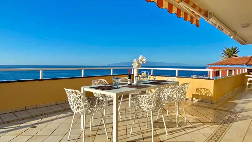 a table and chairs on a balcony overlooking the ocean at Vitacrab Penthouse in erster Meereslinie in Puerto de Santiago