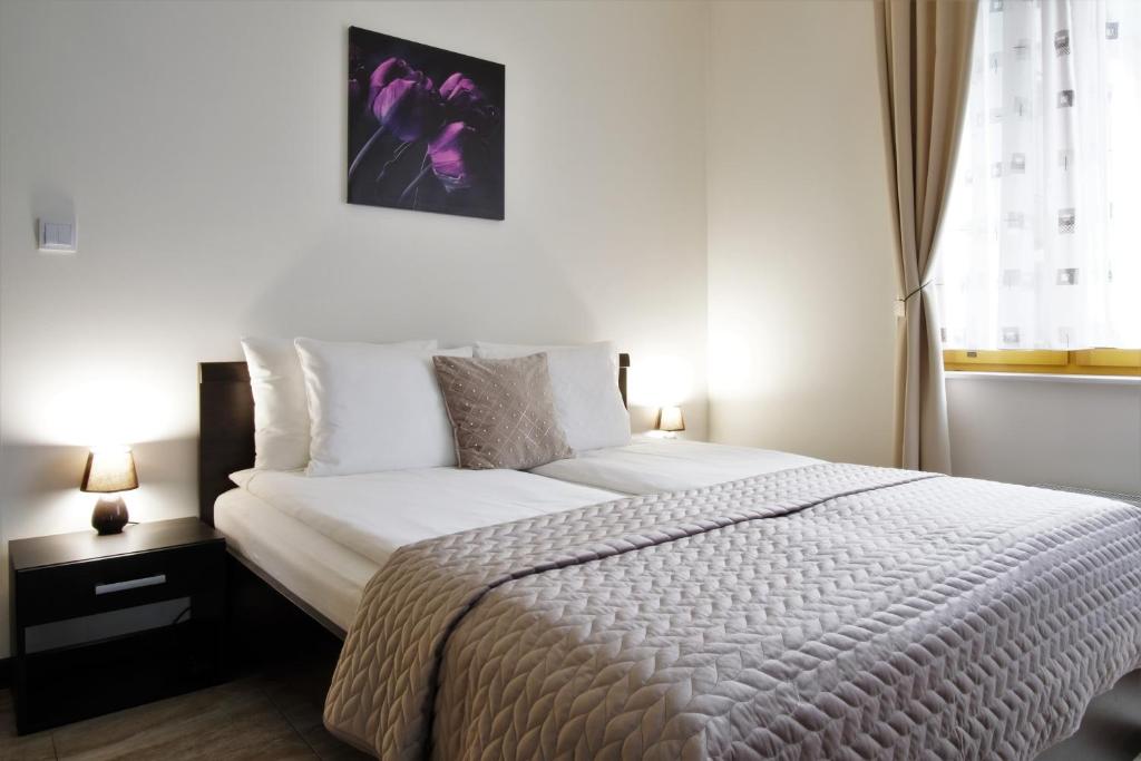 una camera da letto con un grande letto con lenzuola bianche e una finestra di Krak Apartments a Cracovia