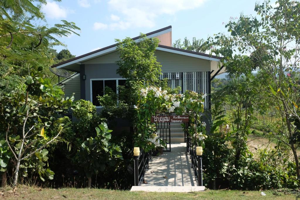 a house with a gate and trees in front of it at Rai Boonsom in Phrao