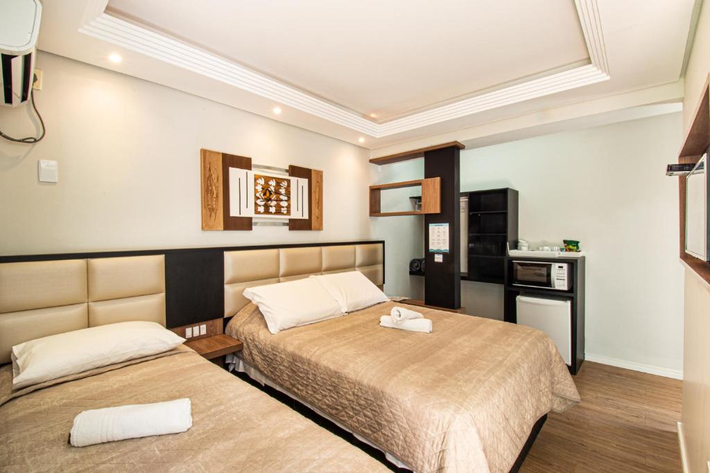 pokój hotelowy z 2 łóżkami i kuchnią w obiekcie Pousada Cristalmar w mieście Bombinhas