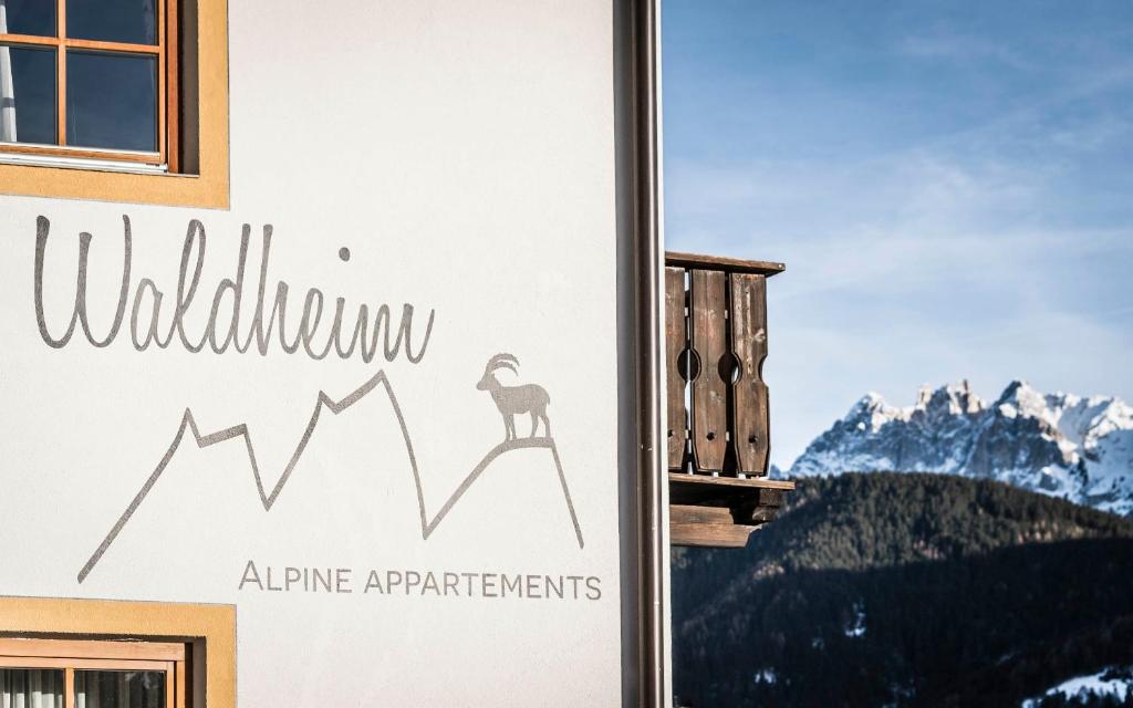 a sign on the side of a building with a mountain at Waldheim Appartements in Bressanone