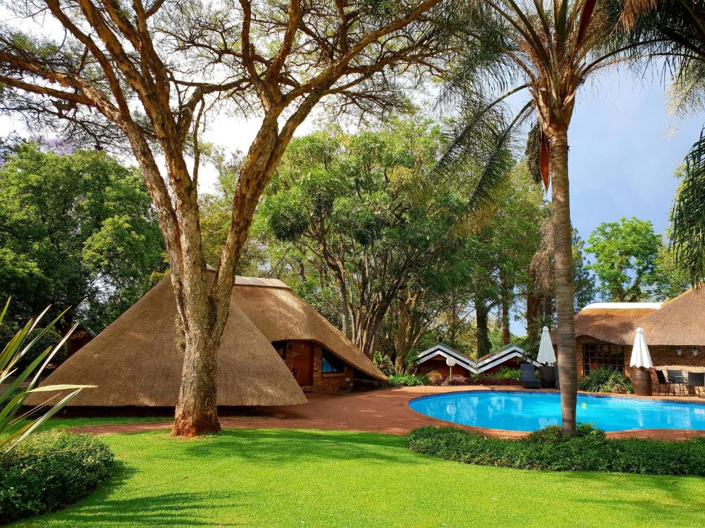 une maison au toit de chaume avec une piscine et des arbres dans l'établissement Haggards on Hilldrop, à Newcastle