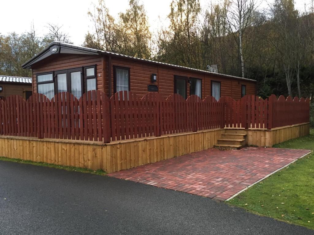 a house with a wooden fence in front of it at 81 The Heathers, Aviemore Holiday Park , Dalfaber rd Aviemore PH22 1PX in Aviemore