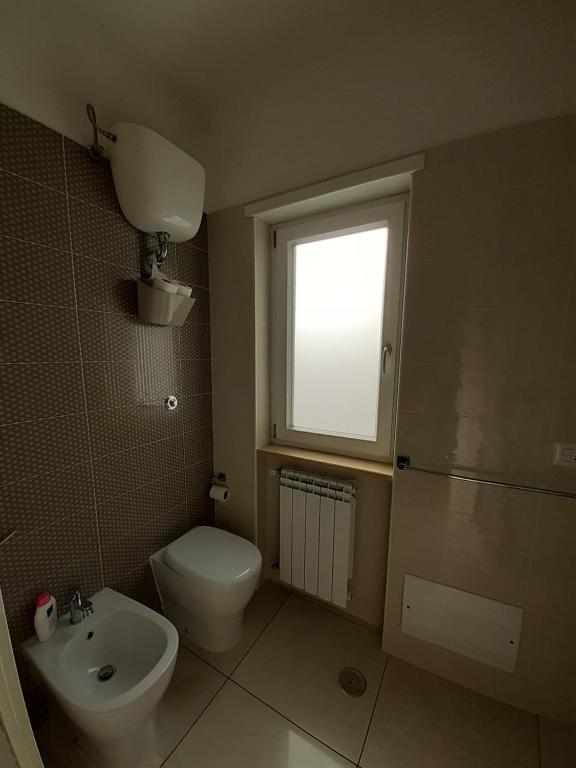 a bathroom with a toilet and a sink and a window at San Marco Beach App Libeccio in Agropoli