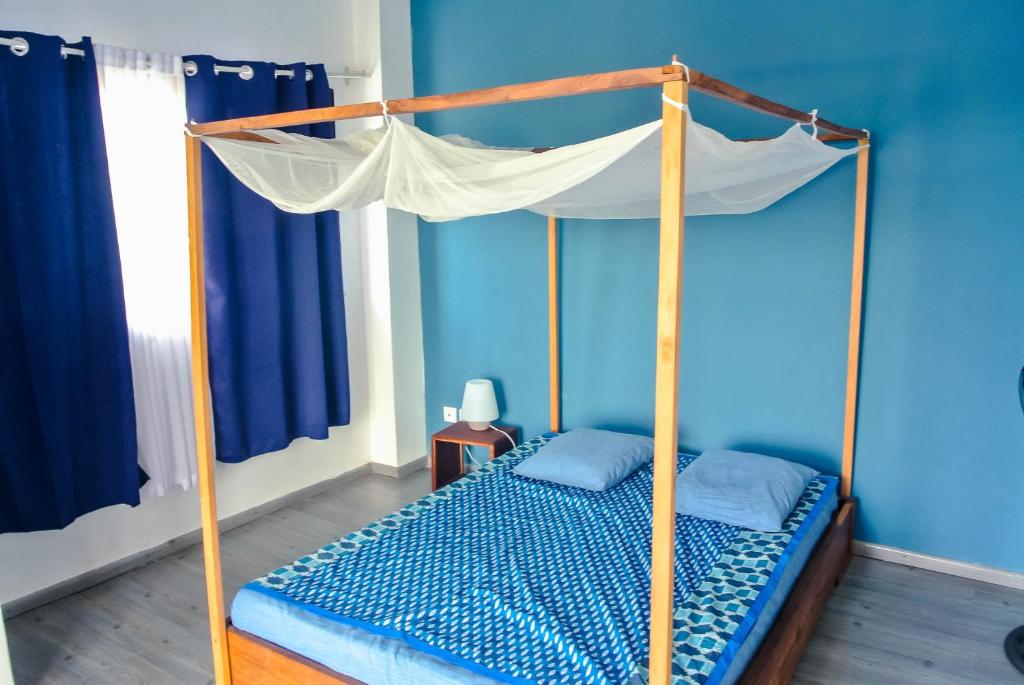 ein Schlafzimmer mit einem Himmelbett in einem blauen Zimmer in der Unterkunft HANIALA BY THE SEA in Mahajanga