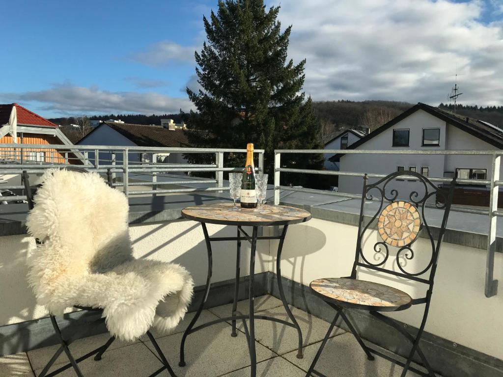 a table and two chairs on a balcony with a bottle of wine at Attika Ferienwohnung in Freiburg -Gundelfingen mit großer Dachterrasse in Gundelfingen