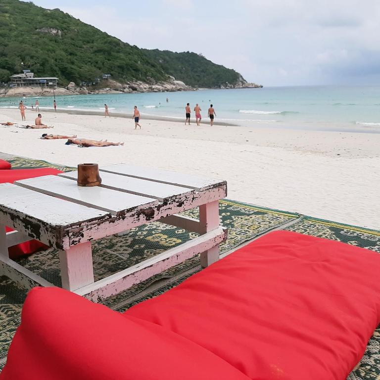 a picnic table on a beach with people in the water at Sunrise Resort- Koh Phangan - SHA Extra Plus in Haad Rin