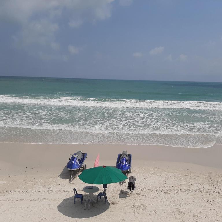 a beach with a table and chairs and an umbrella at Sunrise Resort- Koh Phangan - SHA Extra Plus in Haad Rin