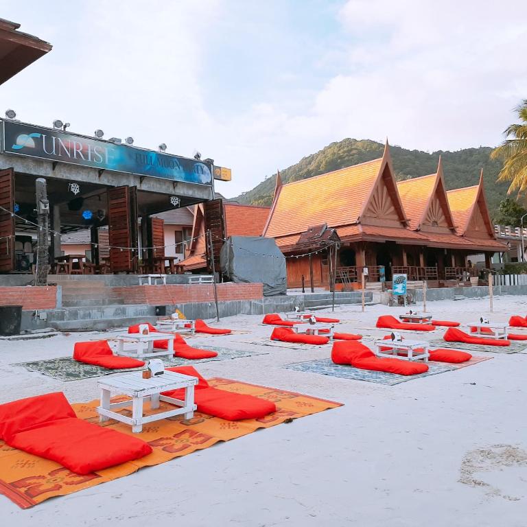 a group of red and white picnic tables in front of a building at Sunrise Resort- Koh Phangan - SHA Extra Plus in Haad Rin