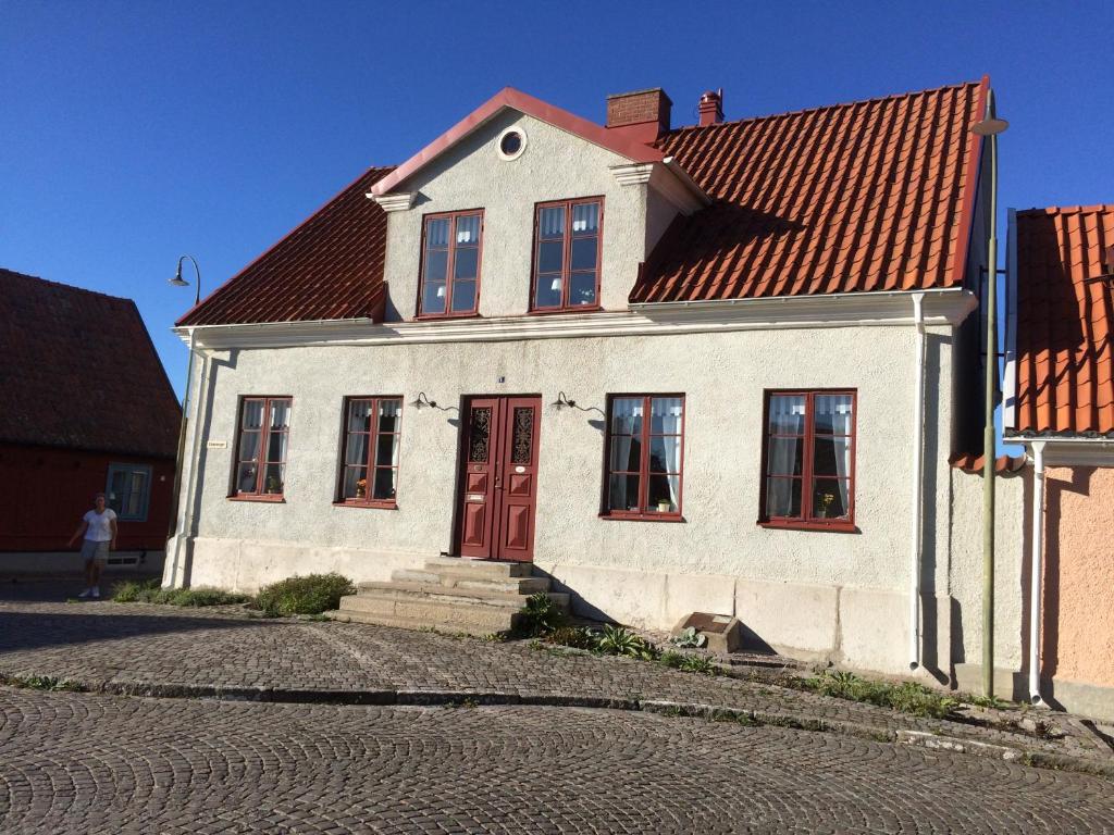 a white house with a red door on a street at Klinttorget 1 in Visby