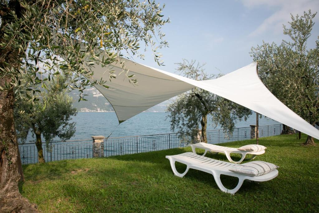 due sedie e un ombrellone bianco sull'erba di IseoLakeRental - La Stallina - Monte Isola a Monte Isola