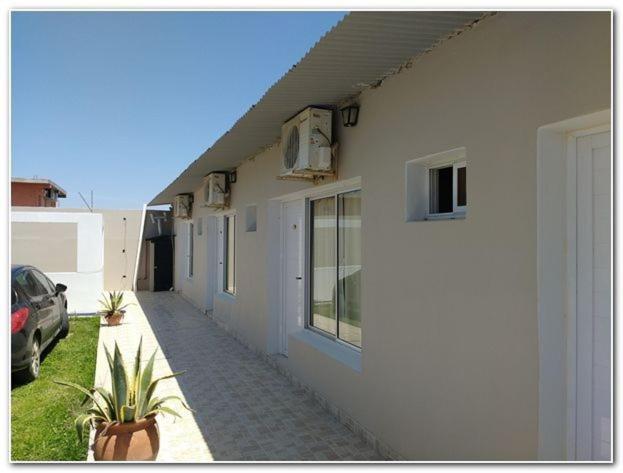 a white building with a car parked next to it at Habitaciones Brisas Místicas in Las Grutas