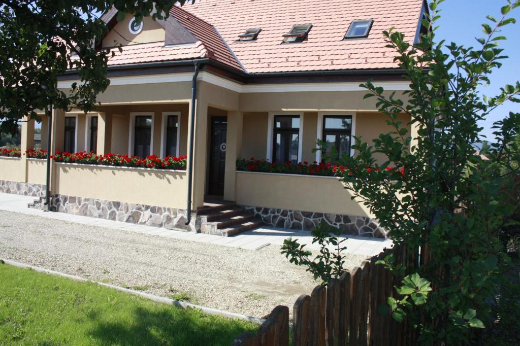 ein Haus mit roten Blumen im Hof in der Unterkunft Pensiune AgroTuristica Horváth-Kert in Borzont