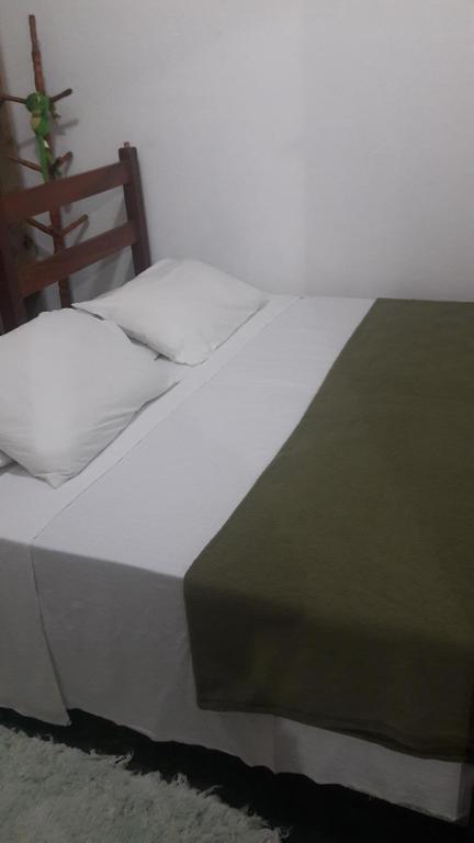 a large white bed with a green and white pillow at Casa folha verde in Trancoso