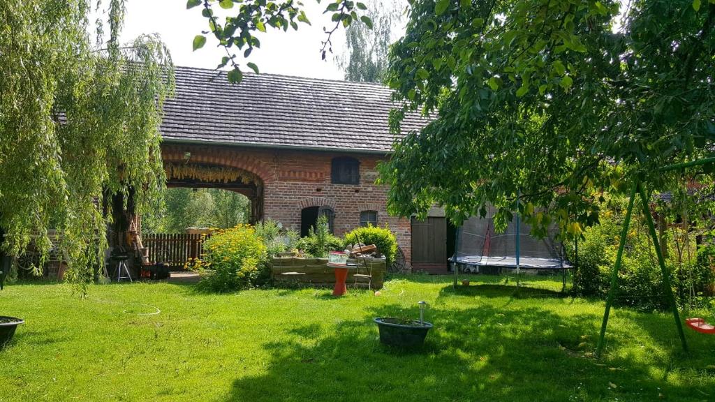 una casa de ladrillo con un patio con césped y árboles en StorchenHof, en Schmogrow