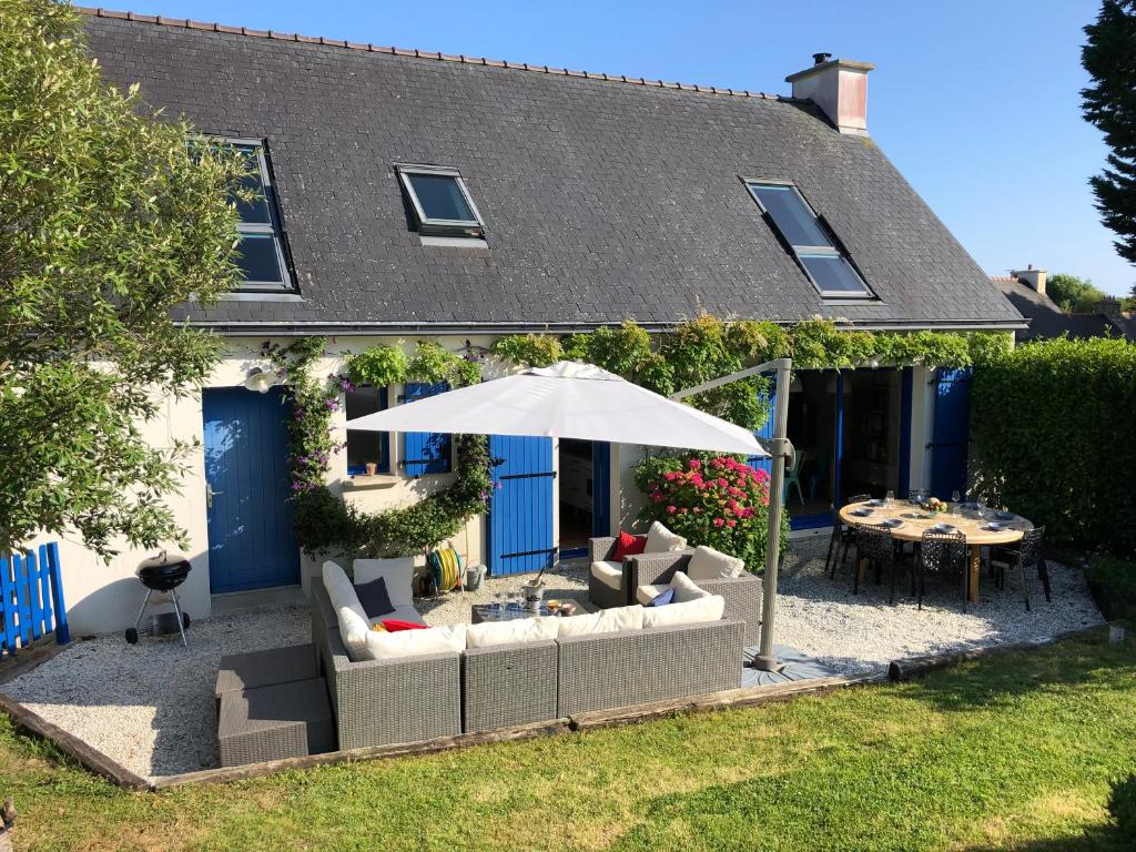 een patio met een tafel en een parasol bij Maison familiale 11 couchages, proche de La Palue in Crozon