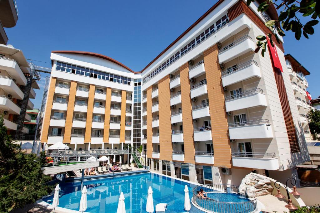 un hotel con piscina frente a un edificio en Alaiye Kleopatra Hotel en Alanya