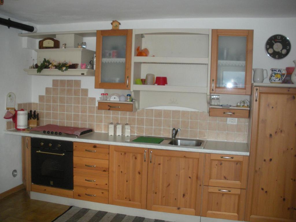 uma cozinha com armários de madeira e um lavatório em Casa Daniela e Giulio em Montesover