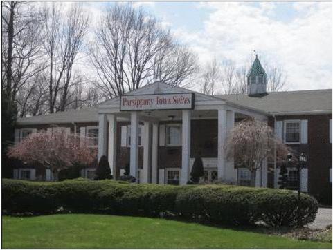 un gran edificio blanco con un cartel para el servicio de traslado a la sala de recuperación en The Parsippany Inn and Suites, en Morris Plains