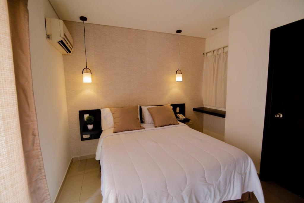 1 dormitorio con 1 cama blanca y 2 almohadas en Hotel Maranata Valledupar, en Valledupar