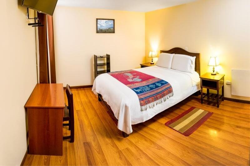 a bedroom with a large bed and a wooden floor at La Casa de Anita in Chivay