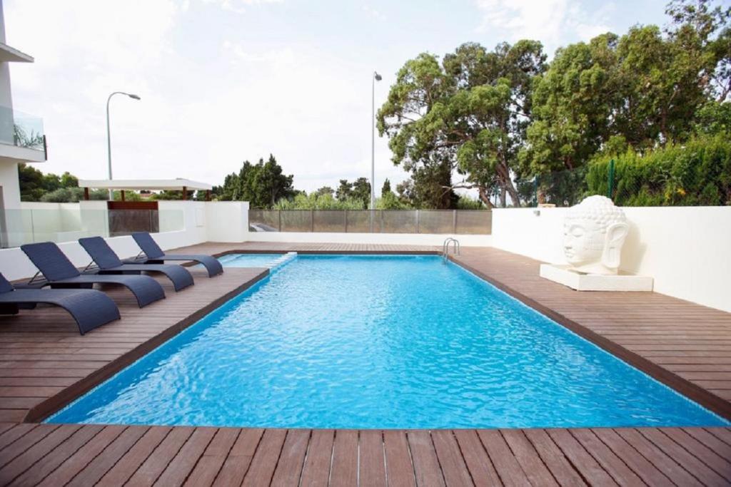 a swimming pool on a patio with chairs on a deck at Tierra Marina Dénia BAJO con jardín in Denia