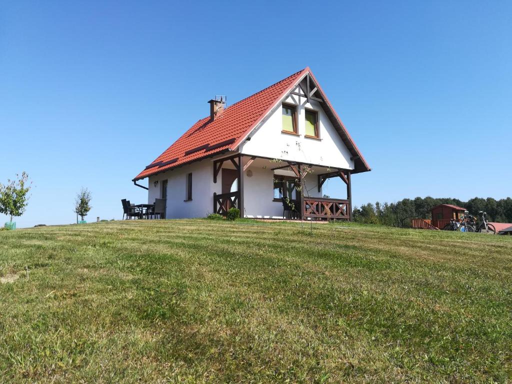a house with a red roof on top of a field at Słoneczne Zacisze in Miłomłyn