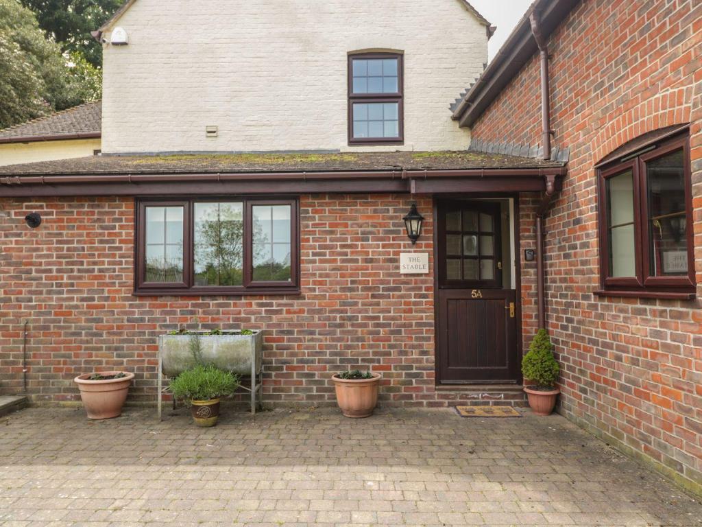 a brick house with potted plants in front of it at The Stable - 2 bed annexe, near Longleat in Warminster