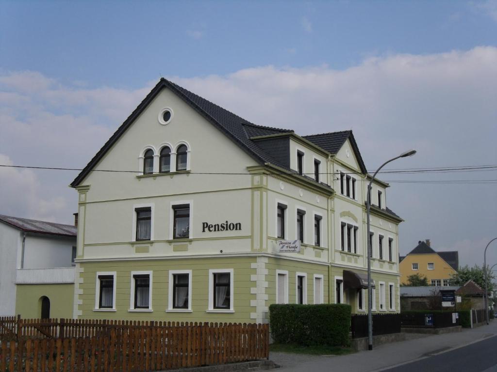 a white building with a black roof at Pension Haufe in Ohorn