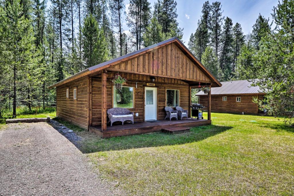 une cabane en rondins dans les bois avec une terrasse couverte dans l'établissement Custom Cabin with Grill and Fire Pit 7 Mi to Glacier!, à Coram