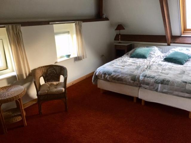 a bedroom with a bed and a chair and a table at B&B De Mersken in Ureterp