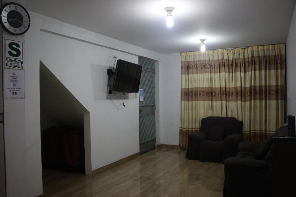 a living room with two chairs and a tv on a wall at Wasi Airport Apartment in Lima