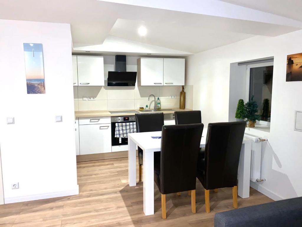 une cuisine avec une table blanche et des chaises noires dans l'établissement Ferienwohnung Wasserkunst, à Bad Harzburg