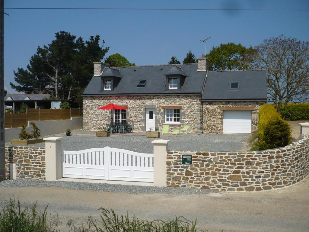 una casa con una valla blanca y una pared de piedra en gite la bretonne, en Plouha