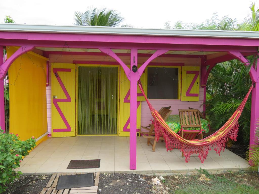 Una casa amarilla y rosa con una hamaca. en Gite KAZ A LILINE, en Le Moule