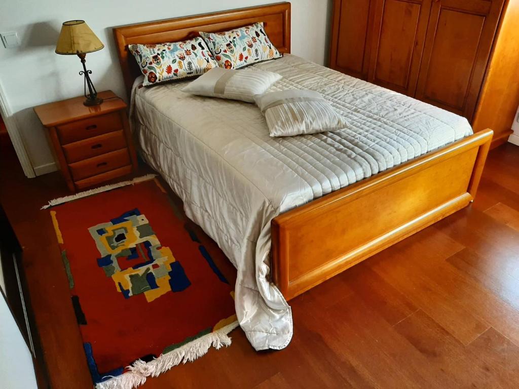 a bedroom with a bed with a wooden frame and a table at Casa Júnior in Arouca