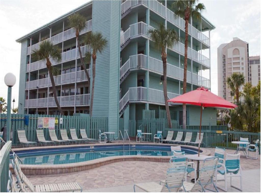 uma piscina com cadeiras e um guarda-sol e um edifício em Clearwater Beach Hotel em Clearwater Beach